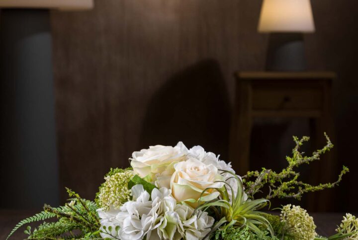 Vista frontale della composizione di fiori con ortensie artificiali, rose e verde realistico, un complemento d'arredo elegante e raffinato per qualsiasi ambiente.