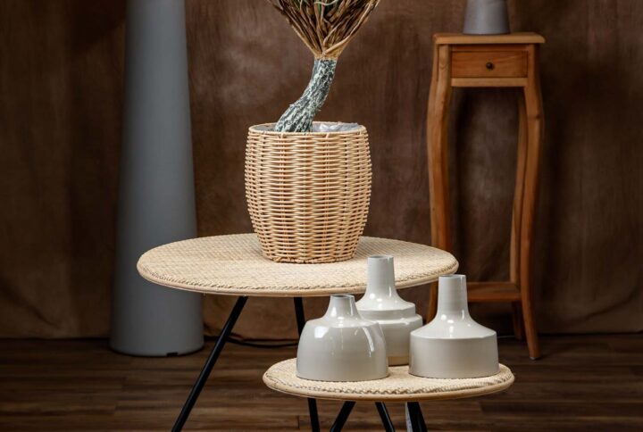 Dettaglio generale della yucca artificiale, con tronco realistico e vaso in vimini posizionato su tavolini di design - La pianta dona un tocco di verde naturale senza necessità di manutenzione