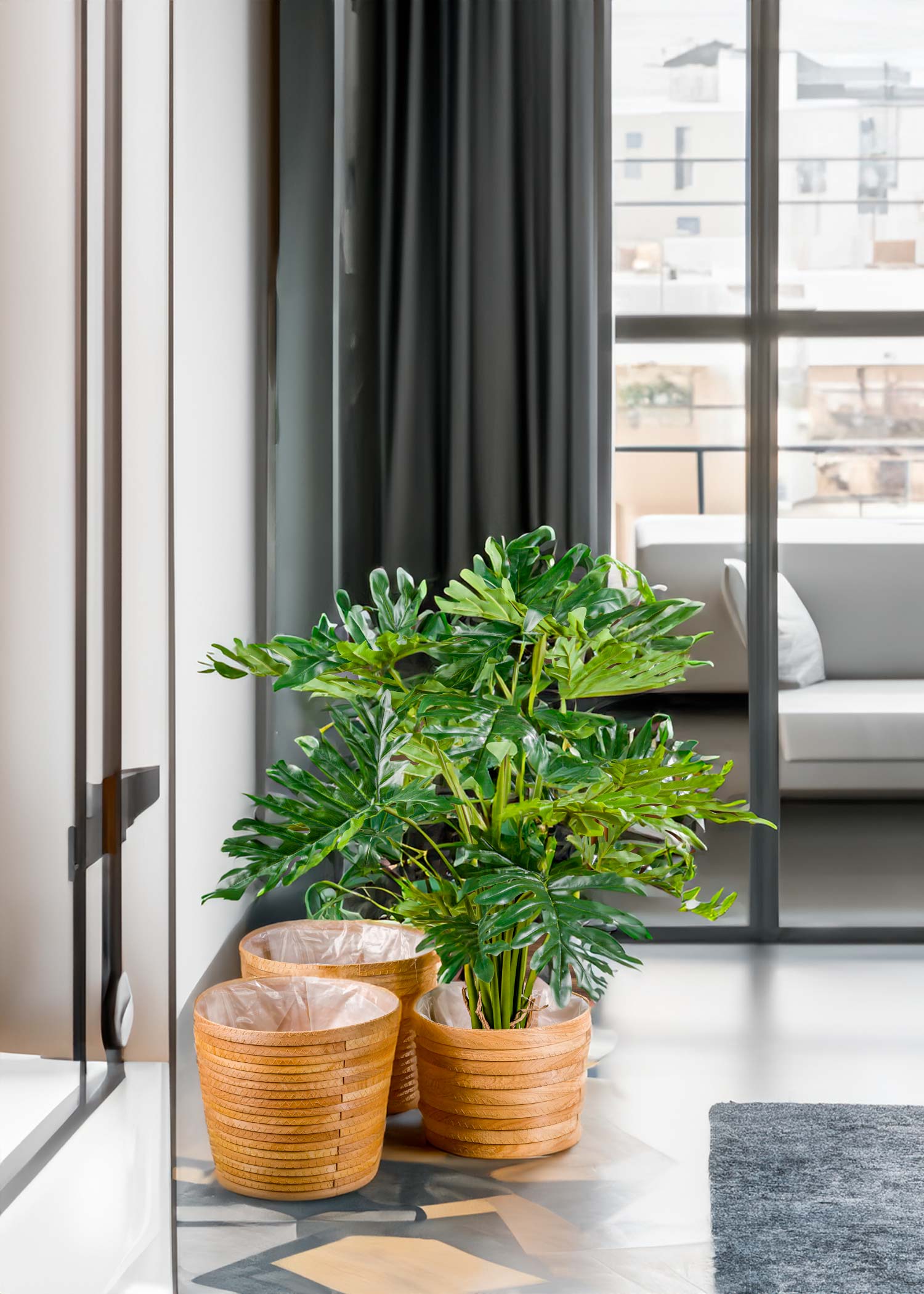 Filodendro Monstera artificiale in un appartamento di design - Il Filodendro Monstera artificiale posizionato in un angolo di un moderno appartamento di design, con un divano e una lampada a sospensione sullo sfondo.