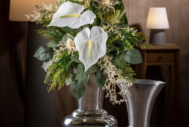 Vista frontale di un mazzo di fiori artificiali finti per cimitero e loculo - un elegante arrangiamento floreale bianco e verde, con anthurium bianchi al centro e fogliame verde intenso