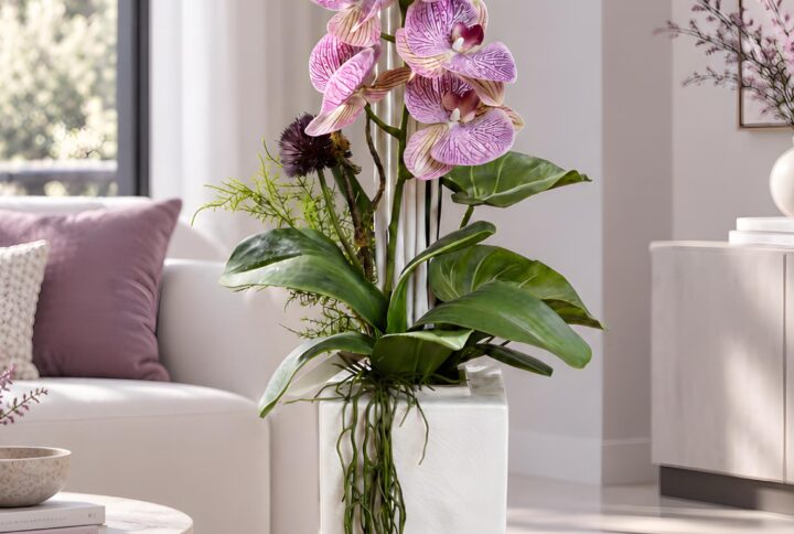 Composizione con orchidee artificiali Real Touch screziate, canette bianche e verde ricadente nel vaso in ceramica, vista completa.