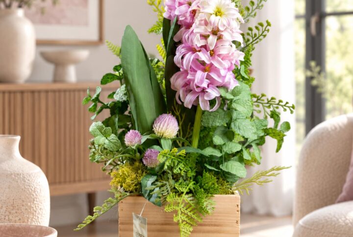 Composizione di fiori artificiali in vaso di legno con fiori rosa e bianco crema e foglie di menta, vista completa ambientata.