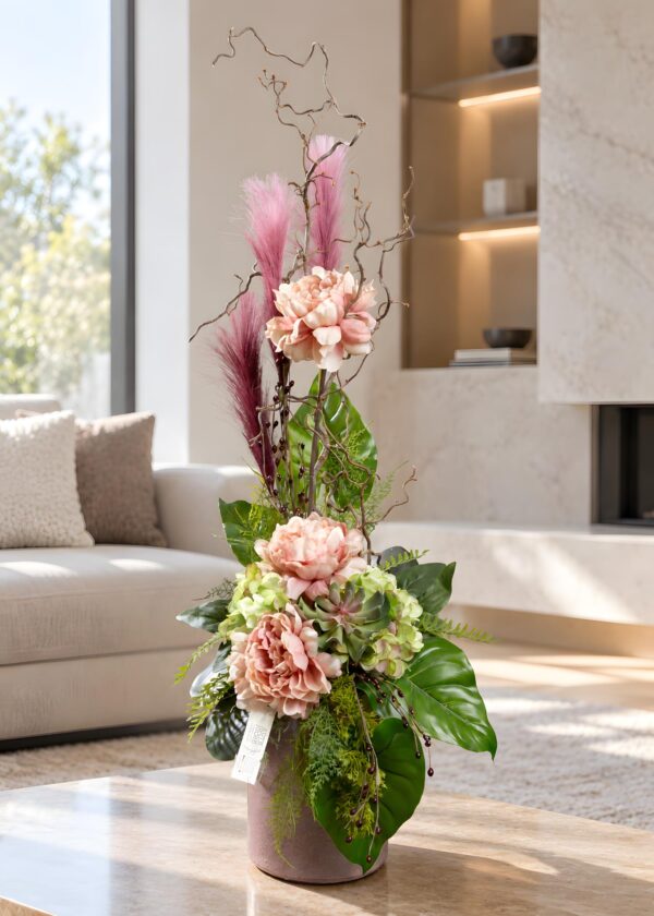 Composizione floreale artificiale rosa in vaso di ceramica, con peonie, ortensie verdi e rami slanciati, ambientata davanti al camino.