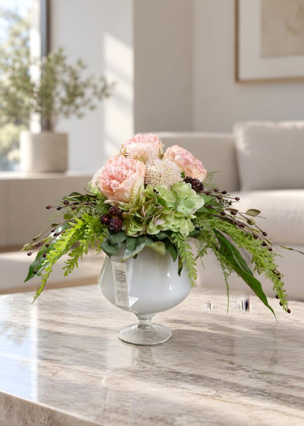 Composizione floreale in coppa di vetro con fiori rosa pastello, Ortensie verde tenue e rami ricadenti, vista completa.