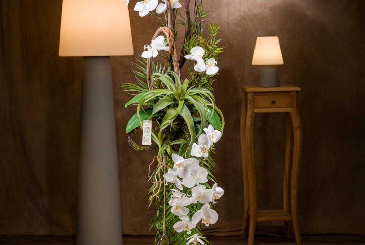 Vista generale della composizione floreale particolare con orchidee, piante grasse e tronchi naturali