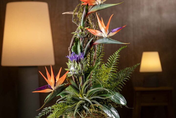 Vista frontale della composizione - Composizione di Sterlizie finte in vaso di vimini con fiori artificiali realistici.