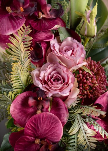 Dettaglio dei fiori di orchidee e rose finte per cimitero, caratterizzati da un vibrante rosa acceso e una cura nei dettagli che conferisce realismo