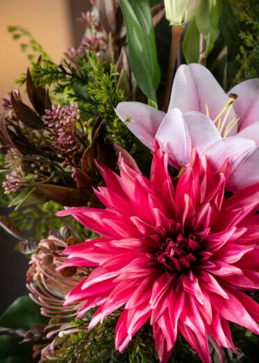 Particolare di un fiore finto, un giglio rosa e una dalia fucsia, che mostrano la qualità realistica della composizione di fiori finti per cimitero.
