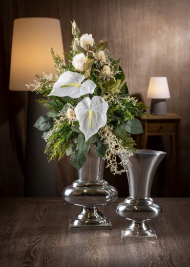 Vista frontale di un mazzo di fiori artificiali finti per cimitero e loculo - un elegante arrangiamento floreale bianco e verde, con anthurium bianchi al centro e fogliame verde intenso