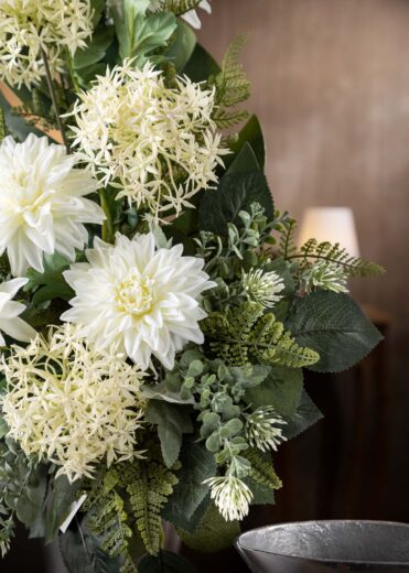 Vista ravvicinata di fiori finti per cimitero in bianco e verde, con dalie e dettagli di allium bianchi per un effetto naturale e raffinato