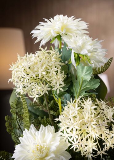 Dettaglio del mazzo di fiori finti per cimitero con dalie bianche e fogliame verde, ideale per un omaggio discreto e rispettoso