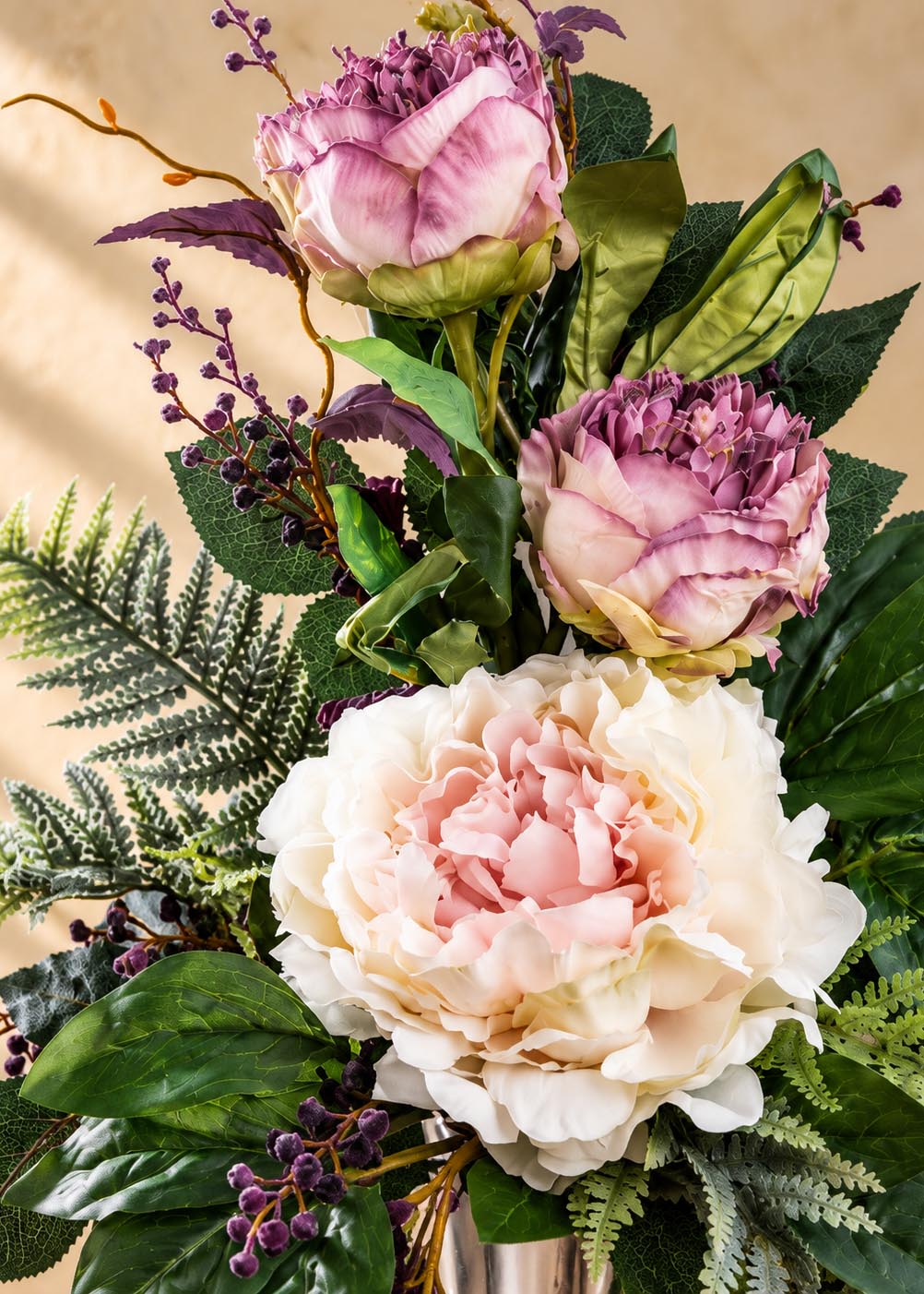 Dettaglio del grande fiore crema con centro rosa e dei due fiori lilla del mazzo artificiale
