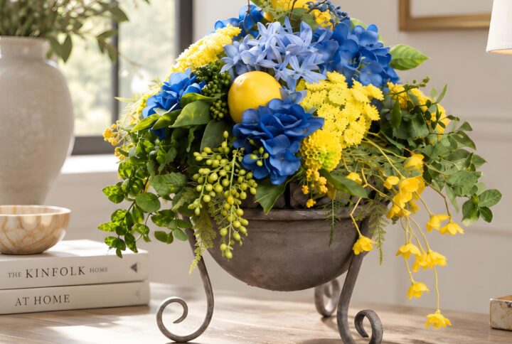 Centrotavola con fiori artificiali blu e gialli in contenitore rialzato