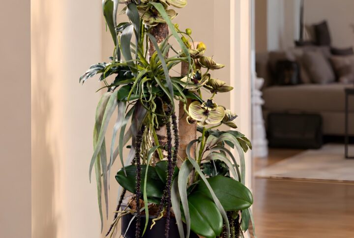 Composizione floreale con tronchi naturali di Betulla, Orchidee screziate e fogliame ricadente nel vaso nero, vista completa.