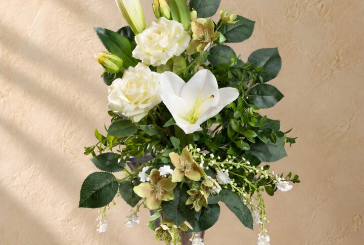 Mazzo artificiale bianco e verde per loculo con gigli e rose, visto frontalmente in un vaso argentato
